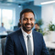 A friendly South Asian man smiling, shown in a professional headshot against a soft blue and white background.