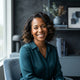 A professional portrait of a diverse woman smiling warmly, reflecting a happy and healthy lifestyle in a modern, neutral-tone